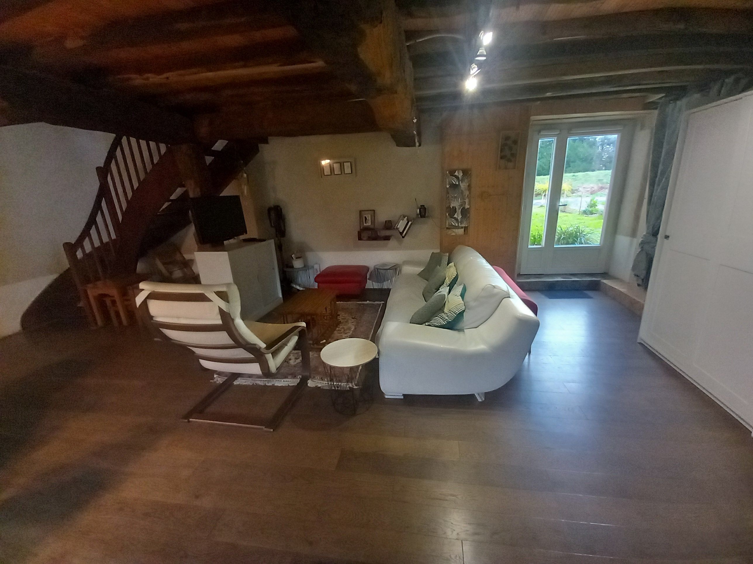 Een woonkamer met een bank, fauteuils, een salontafel en een trap.