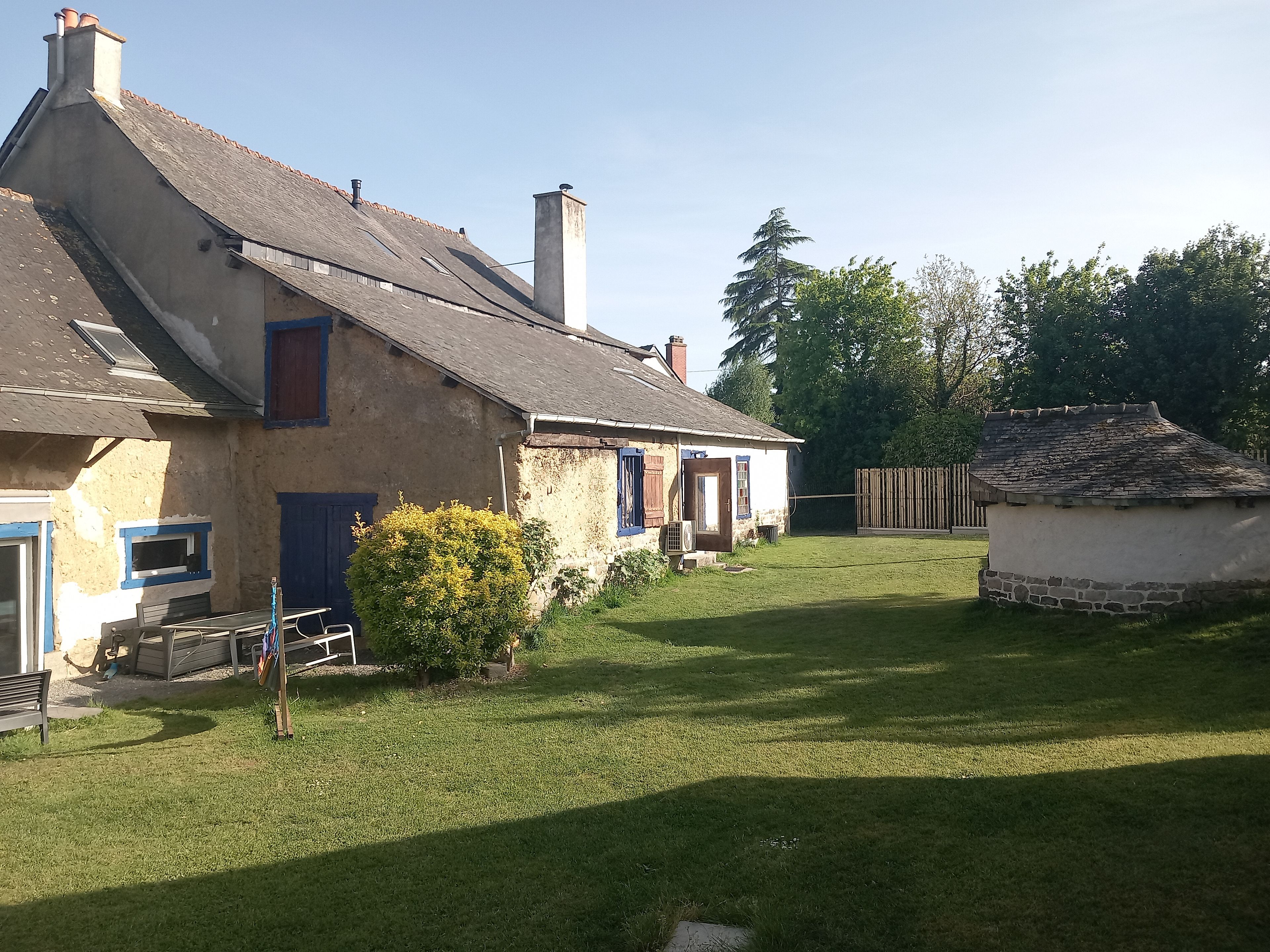 Een landelijk huis met een schuin dak, een kleine tuin en een houten omheining.