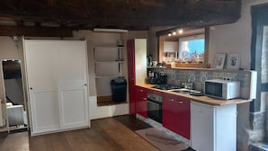 Una cocina compacta con piso de madera, horno empotrado, microondas y pileta.