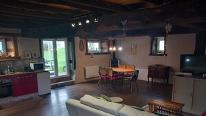 Un salón amplio con sofá, una mesa de comedor con sillas, una zona de cocina con microondas y un televisor.