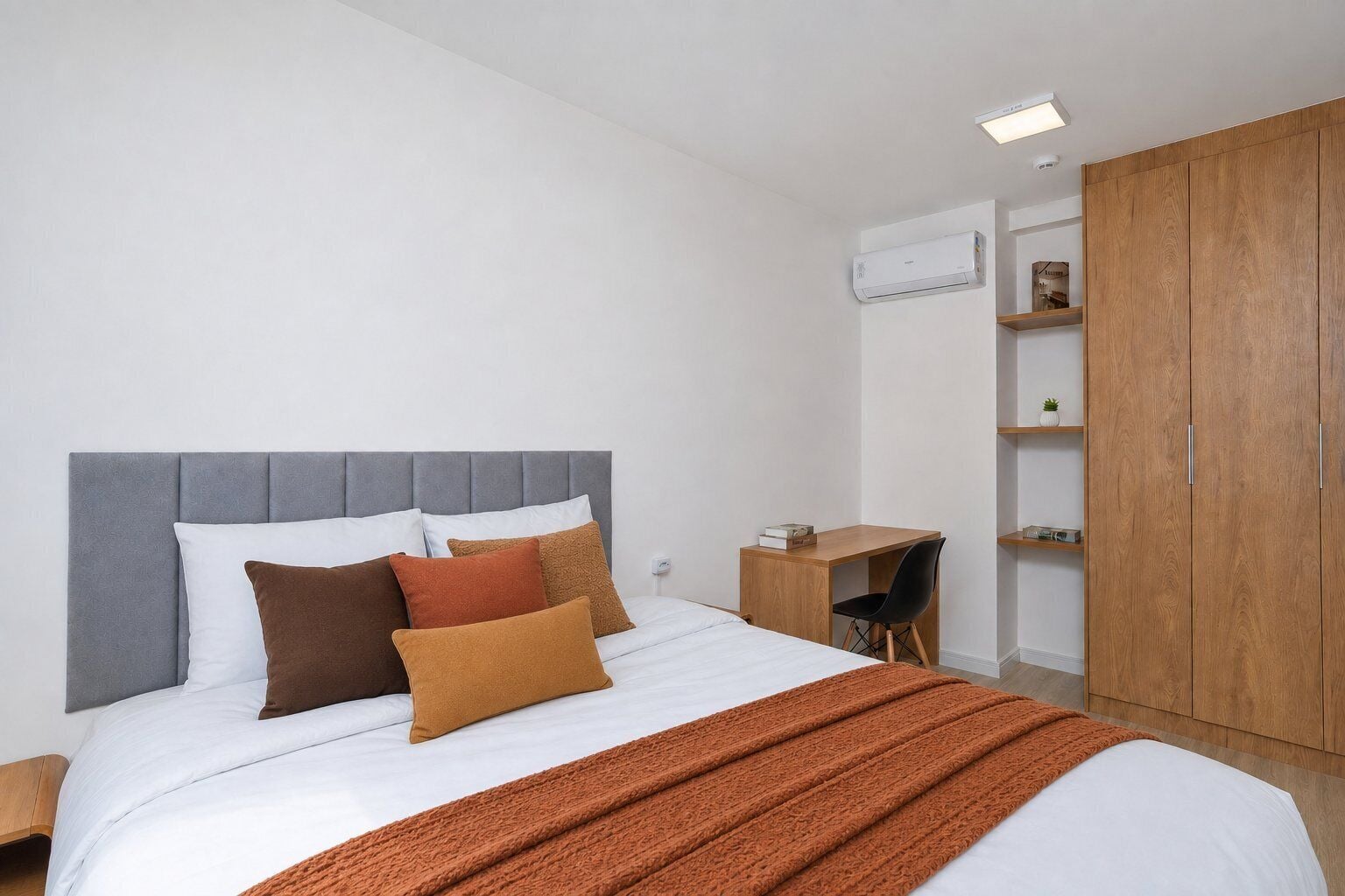A bedroom with a bed, bedside tables, a desk, a chair, and a wardrobe.