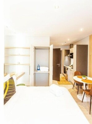 Relax in a cozy space with a neatly made bed, compact kitchenette, and seating area.