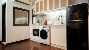 A modern kitchen with a washing machine, a Samsung refrigerator, and a window with blinds. - Fusion Links Apartment (Hanoi)