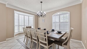 A dining room with a large table, six chairs, and a chandelier. - Amazing Bay Villa Near NASA with Pool & Pool Table (Houston)