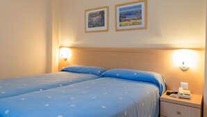 Ein Doppelbett mit blauer Bettwäsche und zwei Wandlampen.