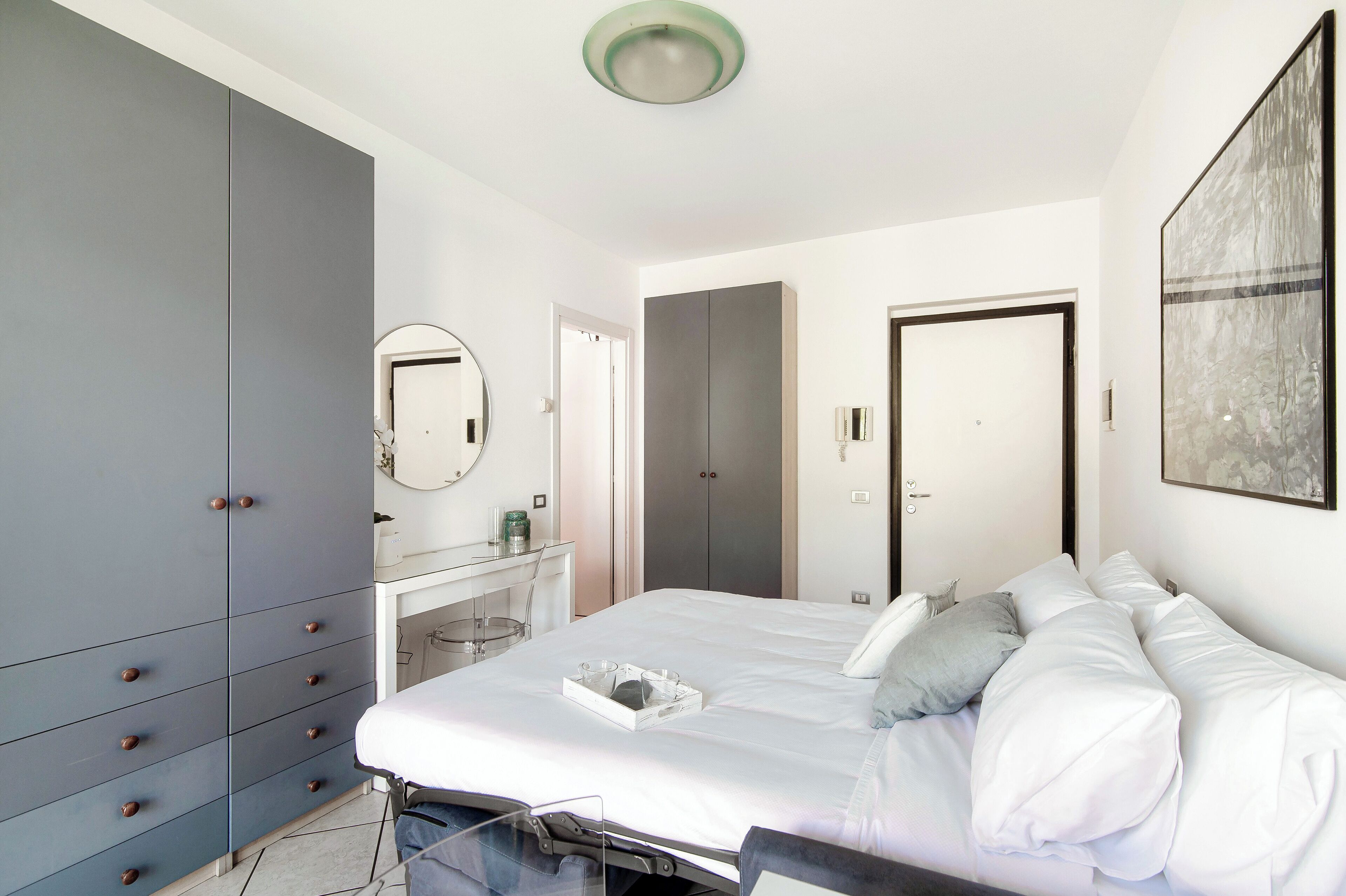 Un dormitorio con cama, armario, escritorio y espejo.