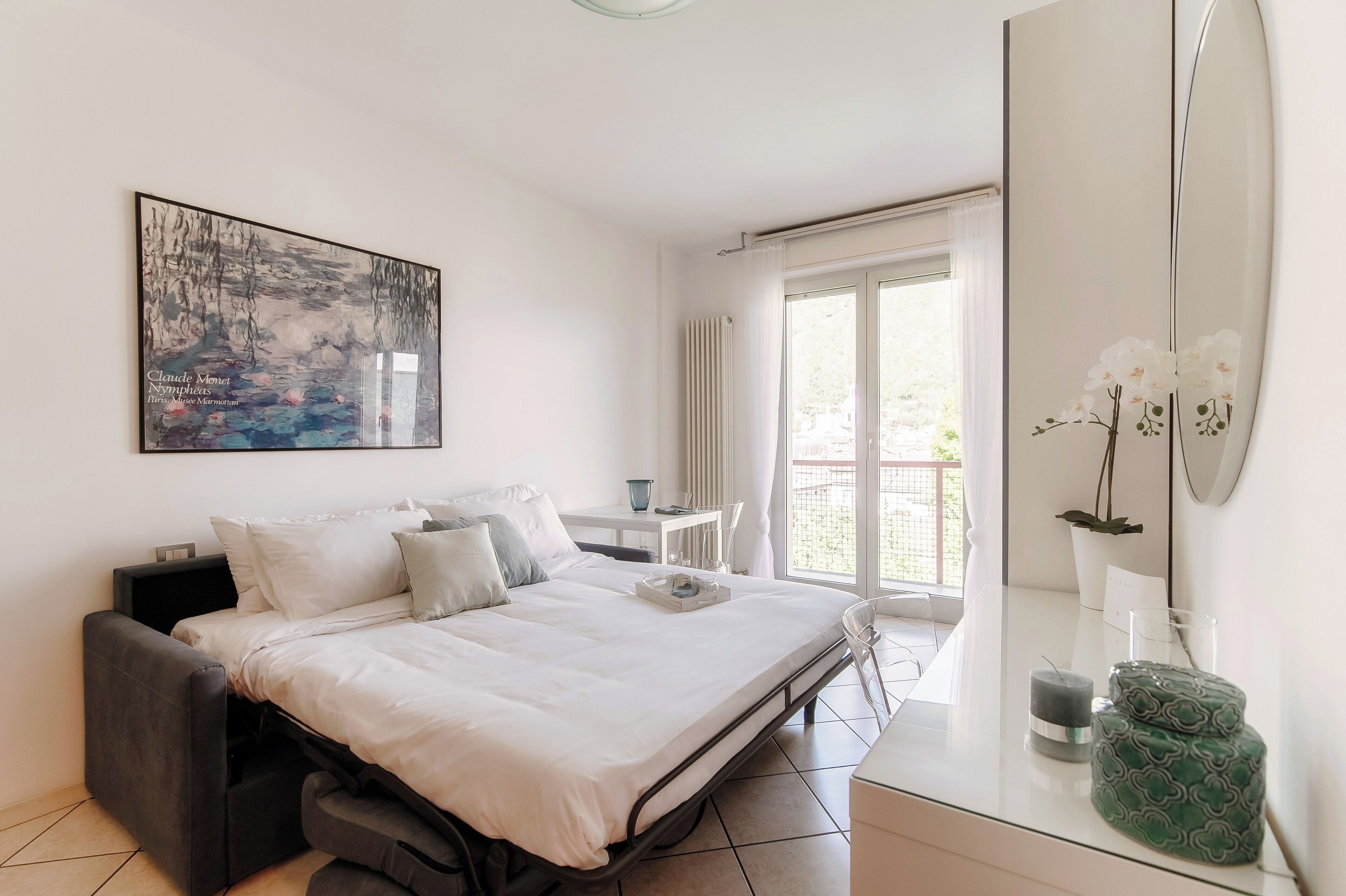 A modern bedroom with a bed, bedside table, and a large window.
