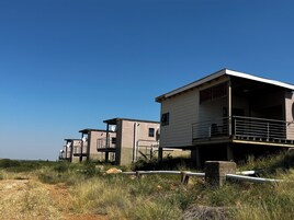 Un edificio moderno frente al mar, con varios niveles, balcones exteriores y una vista despejada del paisaje circundante.