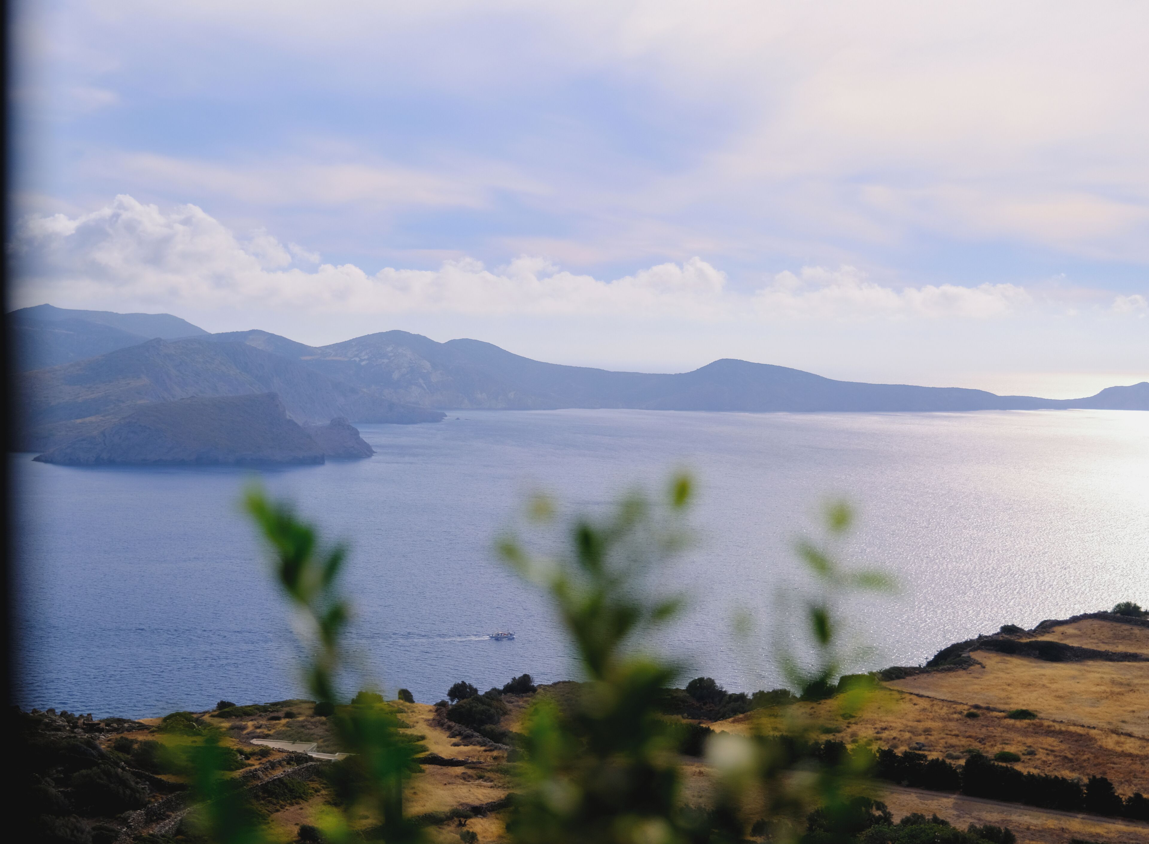 Vista panorâmica de uma paisagem costeira com montanhas ao fundo e um corpo d'água em primeiro plano.