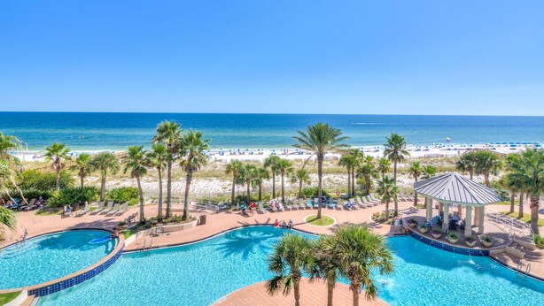 A resort with multiple swimming pools, a beach area with umbrellas, and a gazebo. - Indigo East 406 (Pensacola)