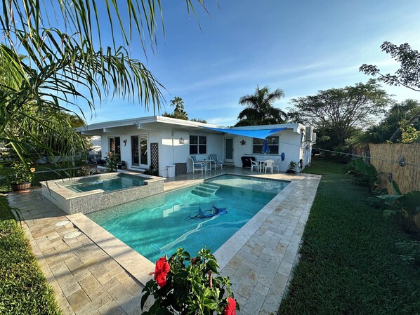 A modern house with a swimming pool, patio furniture, and lush greenery.