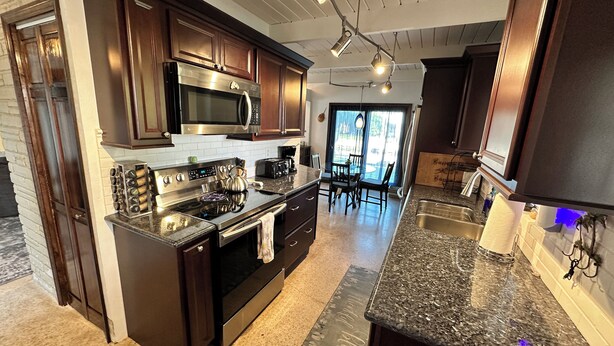A modern kitchen with dark wood cabinets, stainless steel appliances, and a granite countertop. - 3 BR Canal Home in Big Pine Key, FL - Private Pool/Spa - Great Boating Access!!! (Big Pine Key)