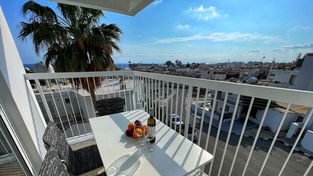 Ein Balkon mit Tisch für zwei Personen, einem Stuhl und Blick auf die Stadtlandschaft.