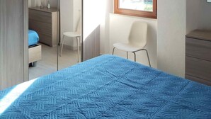 Une chambre à coucher avec un lit, une chaise, une commode et une fenêtre.