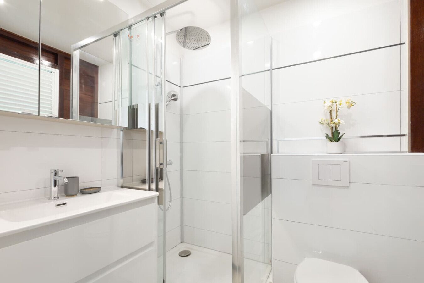 A modern bathroom with a glass-enclosed shower, a white sink, and a toilet.