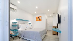 Une chambre à coucher moderne avec un lit, une chaise, un téléviseur et un tableau accroché au mur.