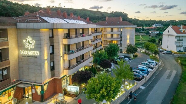 Ein Hotel mit mehreren Balkonen, Sitzgelegenheiten im Freien und einem Parkplatz.