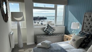 A bedroom with a bed, a window with a view of boats, a radiator, and a lamp. - Ultimate Gorey Retreat (jersey)