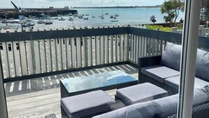 A balcony with wicker furniture and a view of a marina. - Ultimate Gorey Retreat (jersey)
