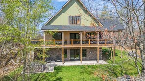 A two-story house with a balcony, stone foundation, and a green roof. - Big and Boulder by Taylor Made Deep Creek (McHenry)