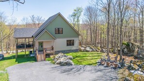 A two-story house with a porch, a stone foundation, and a fire pit area. - Big and Boulder by Taylor Made Deep Creek (McHenry)