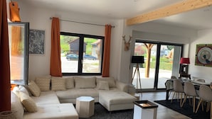 Ein modernes Wohnzimmer mit einer Eckcouch, einem Couchtisch und einem Essbereich mit Stühlen und Tisch.