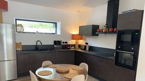 Eine moderne Küche mit Essbereich, ausgestattet mit einem runden Tisch und Stühlen, einem Einbauofen und einem Fenster, das natürliches Licht hereinlässt.