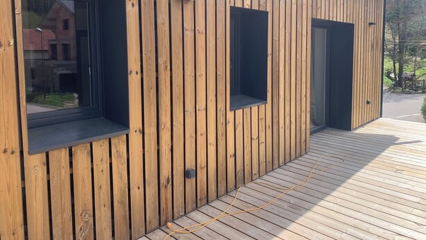 Ein Holzgebäude mit großen Fenstern und Türen.