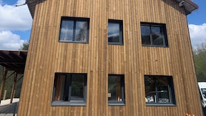 Ein mehrstöckiges Holzgebäude mit großen Fenstern und einem geneigten Dach.