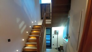 Eine Treppe mit Holzboden und Geländer, die zu einer Zwischenebene mit einer Tür führt.