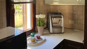 Una cocina con microondas, cafetera y ventana con persianas.