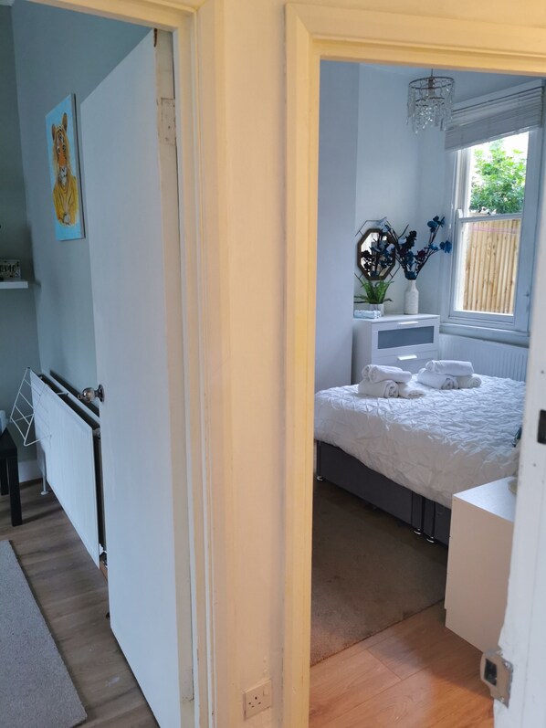 Un dormitorio con cama, ventana con vistas, radiador y un cuadro en la pared.