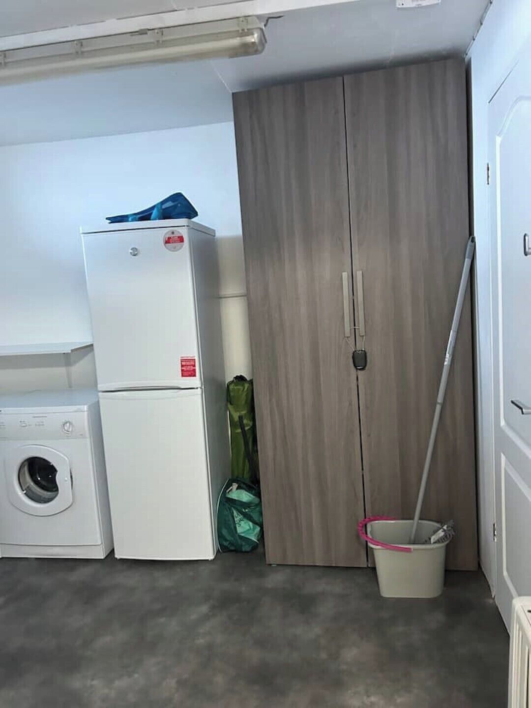 A laundry room with a washing machine, a dryer, and a wooden wardrobe.