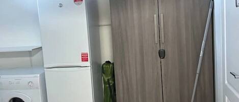 A laundry room with a washing machine, a dryer, and a wooden wardrobe.