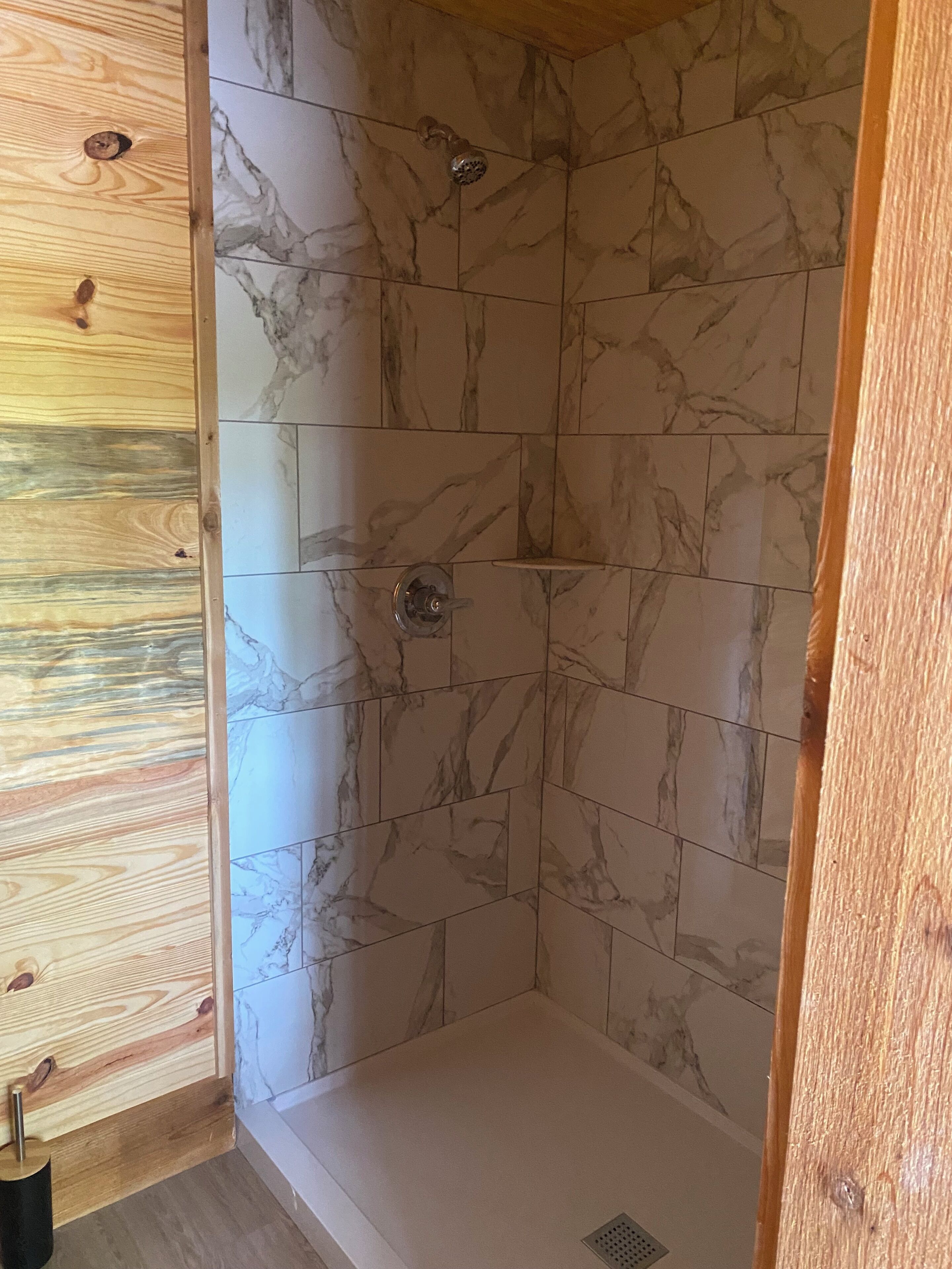 Una doccia con piastrelle in marmo e struttura in legno.