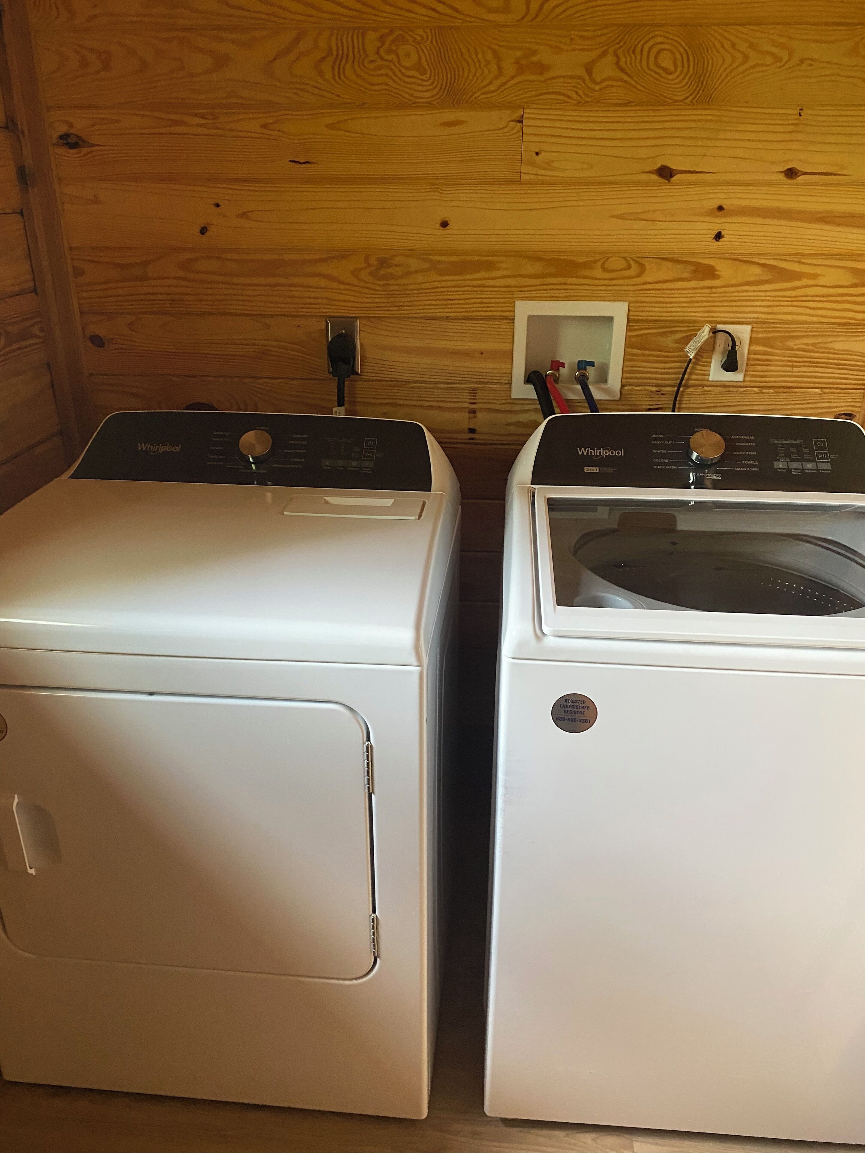 Dos lavadoras Whirlpool blancas en una habitación de madera con un revestimiento de madera.