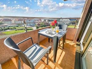 Un balcón con una mesa dispuesta para el desayuno, una silla y vistas a la ciudad.