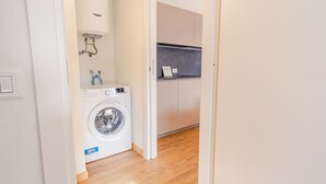 Een wasserette met een voorlader wasmachine, een boiler en een aanrecht met een wasbak.
