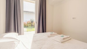 Et hotelværelse med en seng, et vindue med gardiner og udsigt til en have.