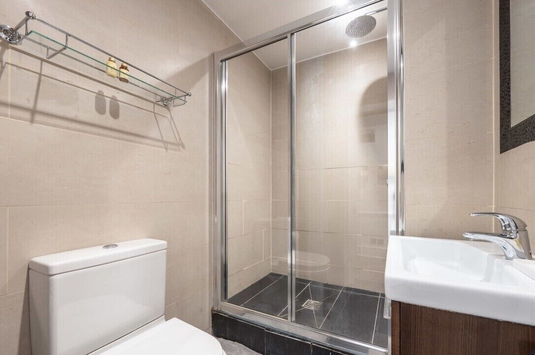 Ein modernes Badezimmer mit Glasdusche, weißer Toilette und Waschbecken mit Spiegel.