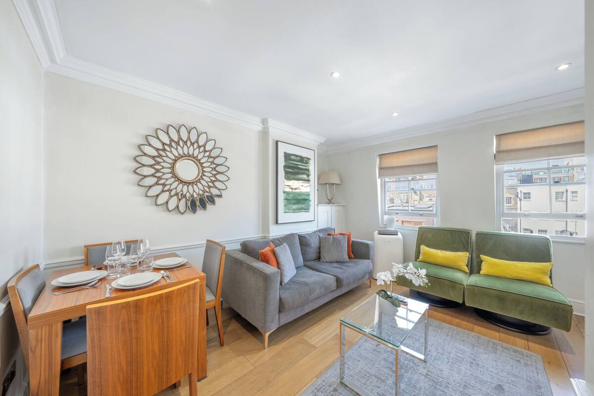 A modern living room with a dining table, sofa, and large windows.