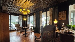 A room with a wooden floor, a chandelier, a dining table with chairs, and large windows with curtains. - The Boho Buffalo Inn (Buffalo)
