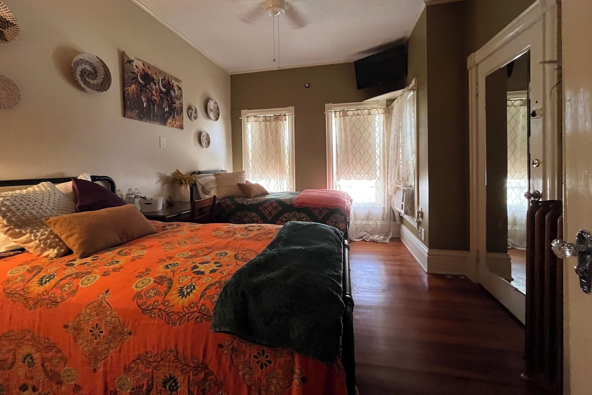 A bedroom with two beds, a ceiling fan, and a door leading to another room.