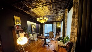 A room with a wooden floor, a chandelier, a chessboard, and a large window with curtains. - The Boho Buffalo Inn (Buffalo)