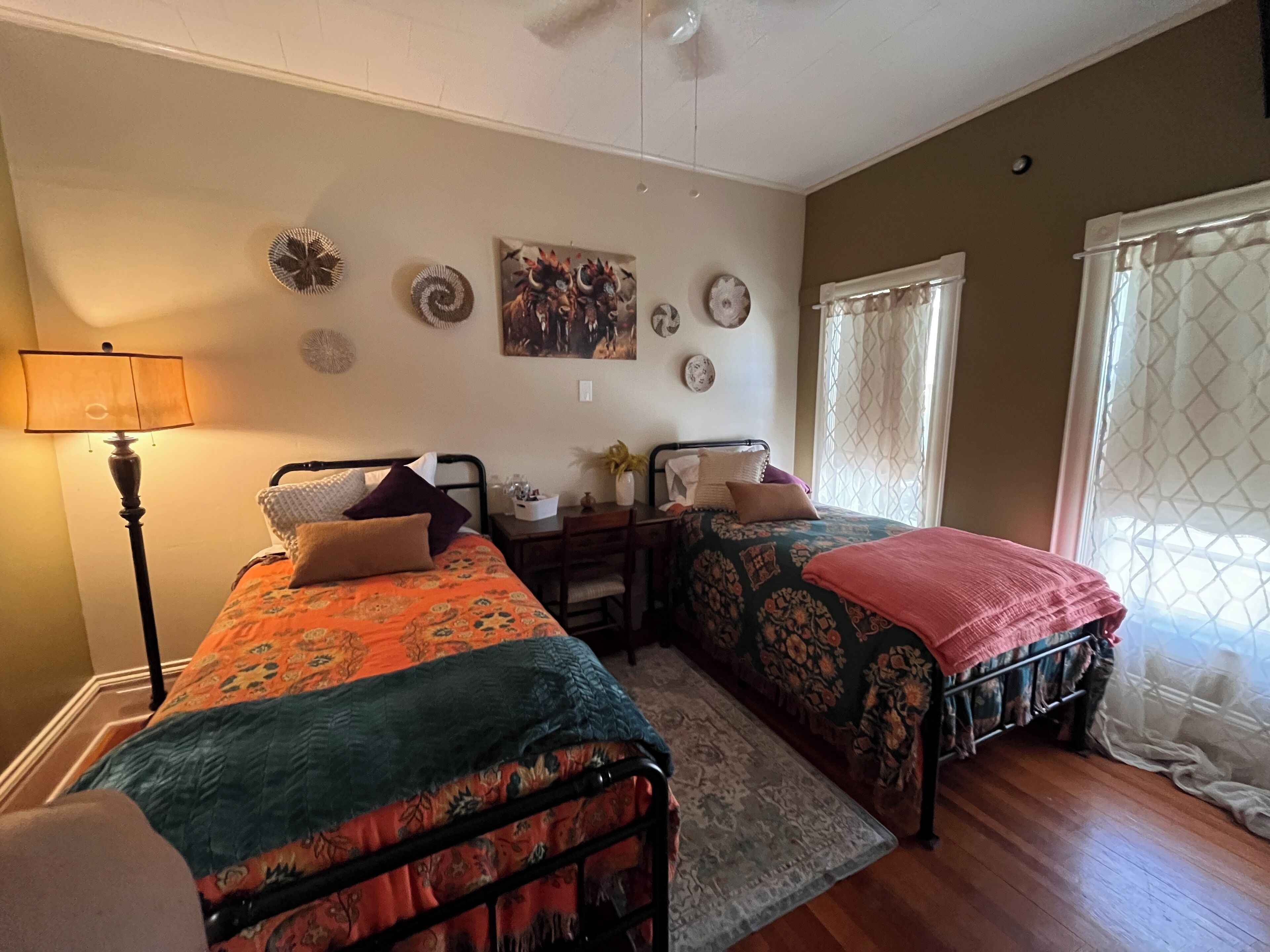 A bedroom with two beds, a desk, and a lamp.