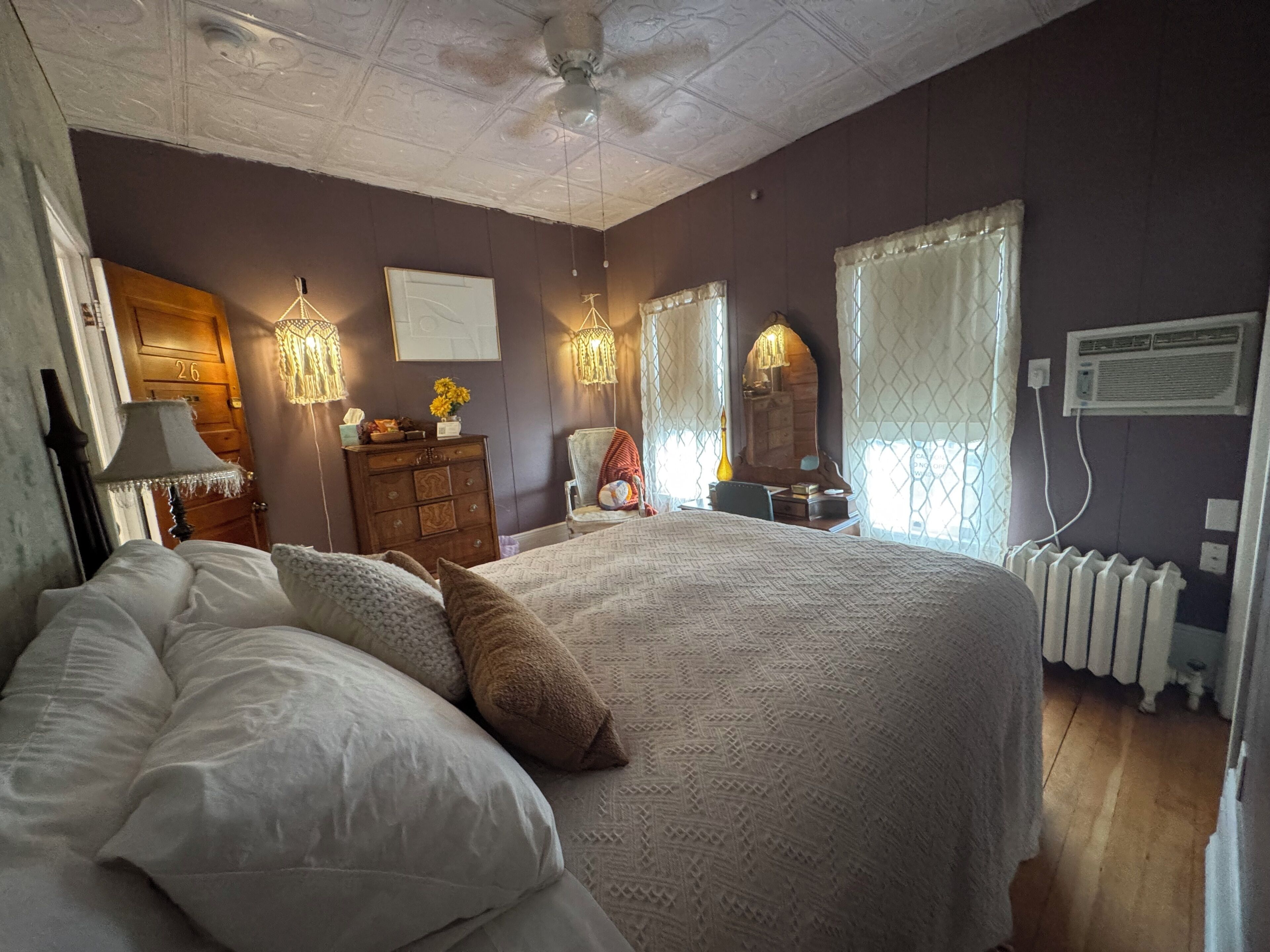 A bedroom with a large bed, a dresser, a chair, and a radiator.