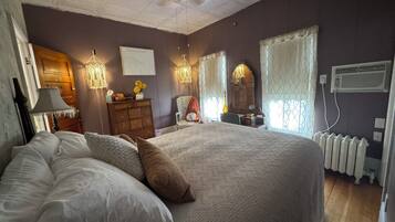 A bedroom with a large bed, a dresser, a chair, and a radiator.
