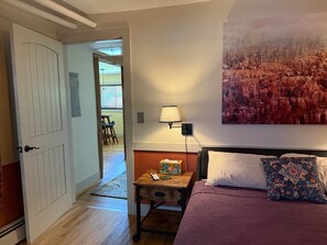 A hotel room with a bed, a nightstand, a lamp, and a painting on the wall.