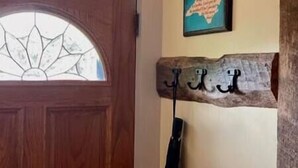 Eine Holztür mit Glasfeld und einem rustikalen Schild mit Haken an der Wand.