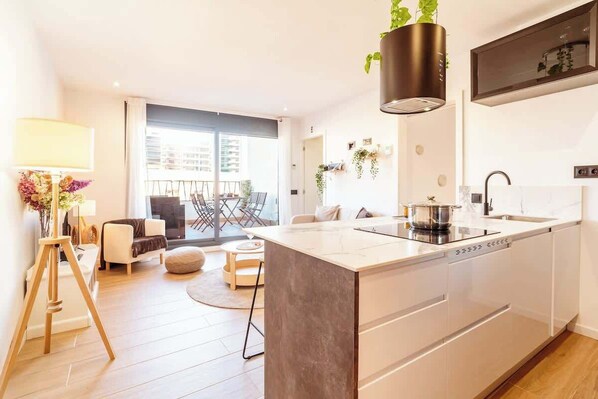 A modern kitchen with a central island, a dining area with a table and chairs, and a balcony with a view.